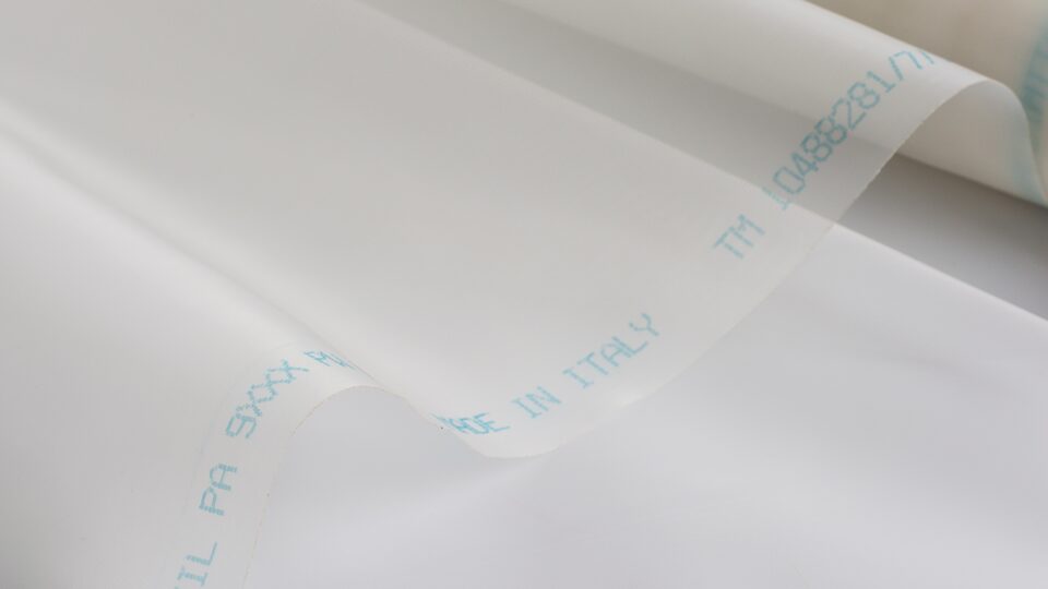 Close-up of a white sheet or film with light blue 'Made in Italy' text along the folded edge.